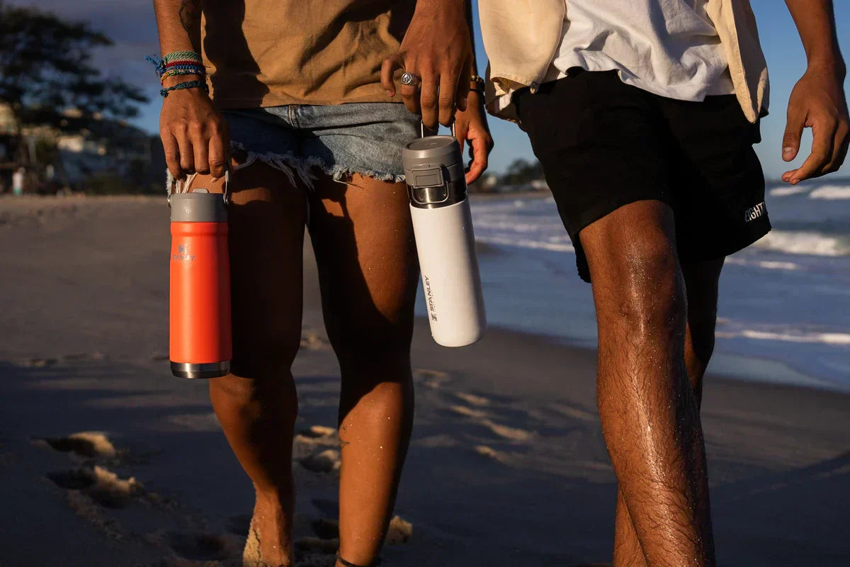 Duas pessoas caminhando na praia, sabendo se a garrafa Stanley digital é original ou não.